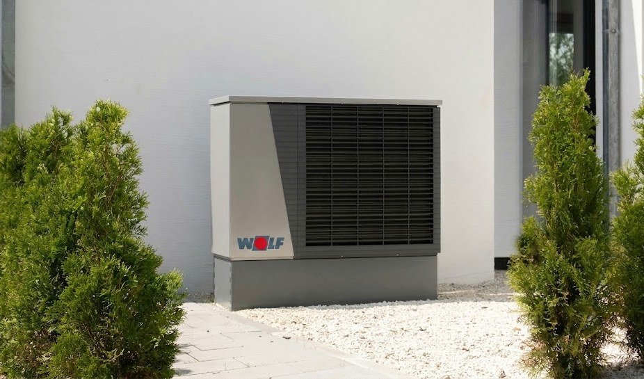 Außengerät einer Wärmepumpe neben einem Wohnhaus